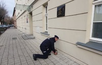 policjant pod tablicą pamiątkową zapala znicz